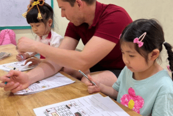 Teacher Brendan Ross Pitt at a table with his students in Thailand